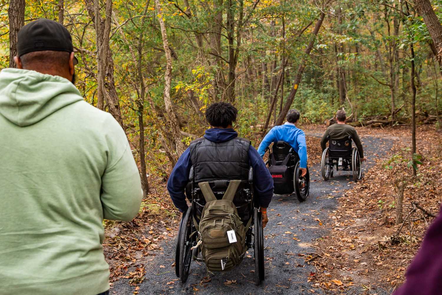 Three men in manual wheelchairs on nature trail
