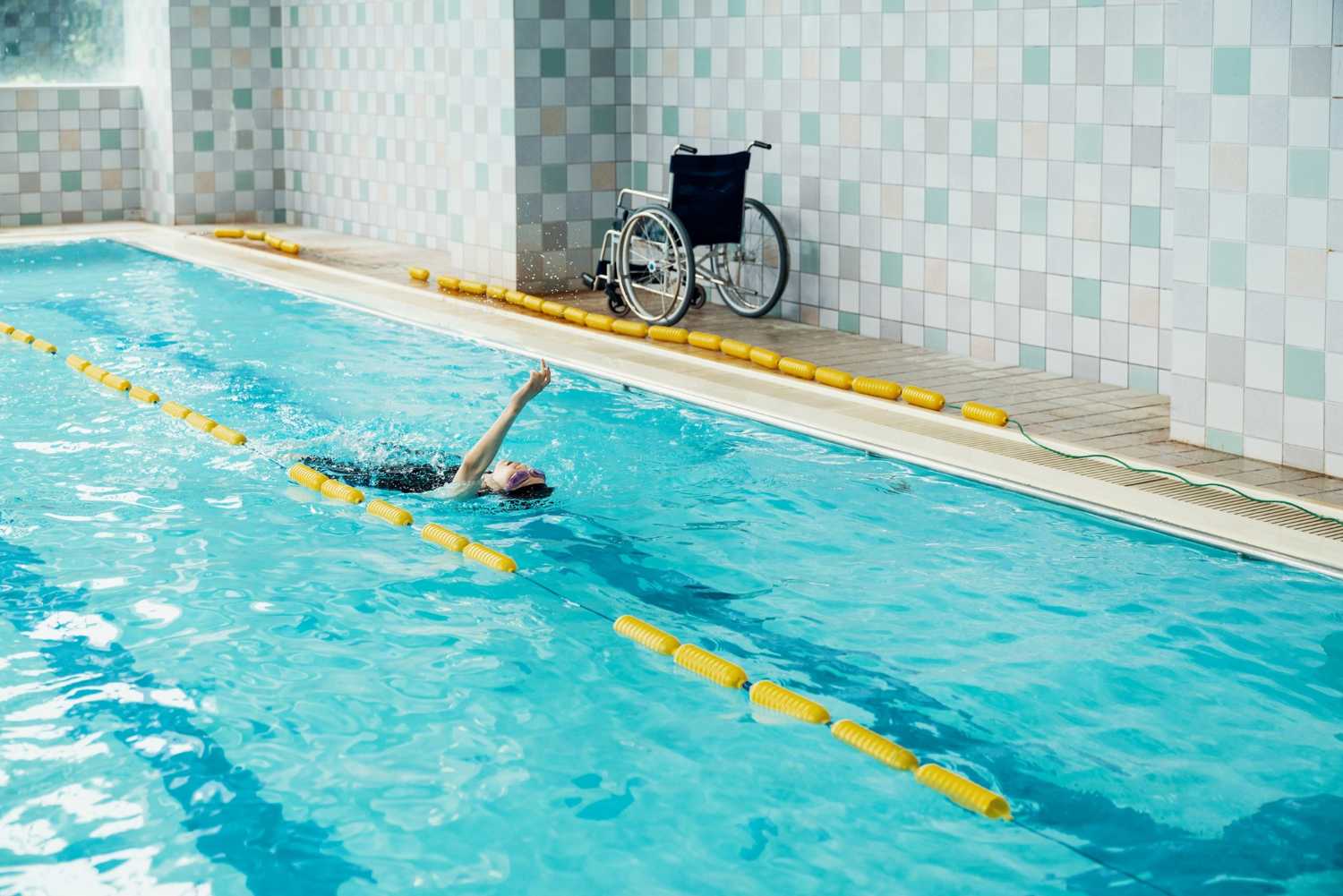 Person swimming in pool - wheelchair next to pool