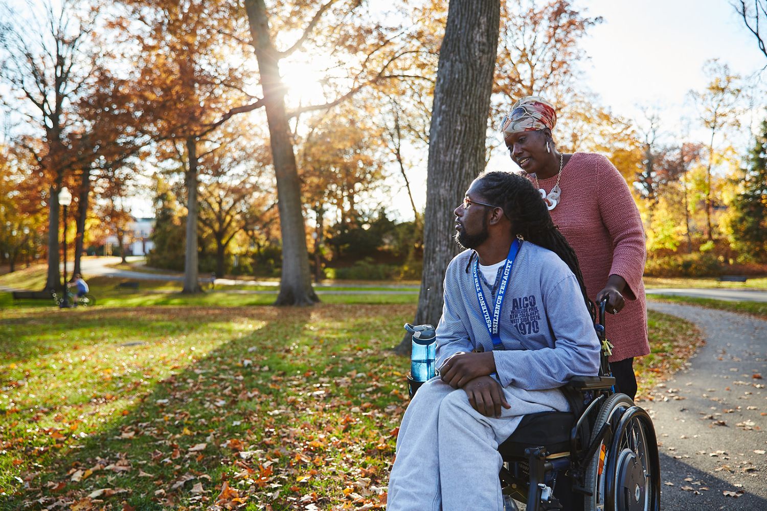 A woman pushing a man in wheelchair on trail
